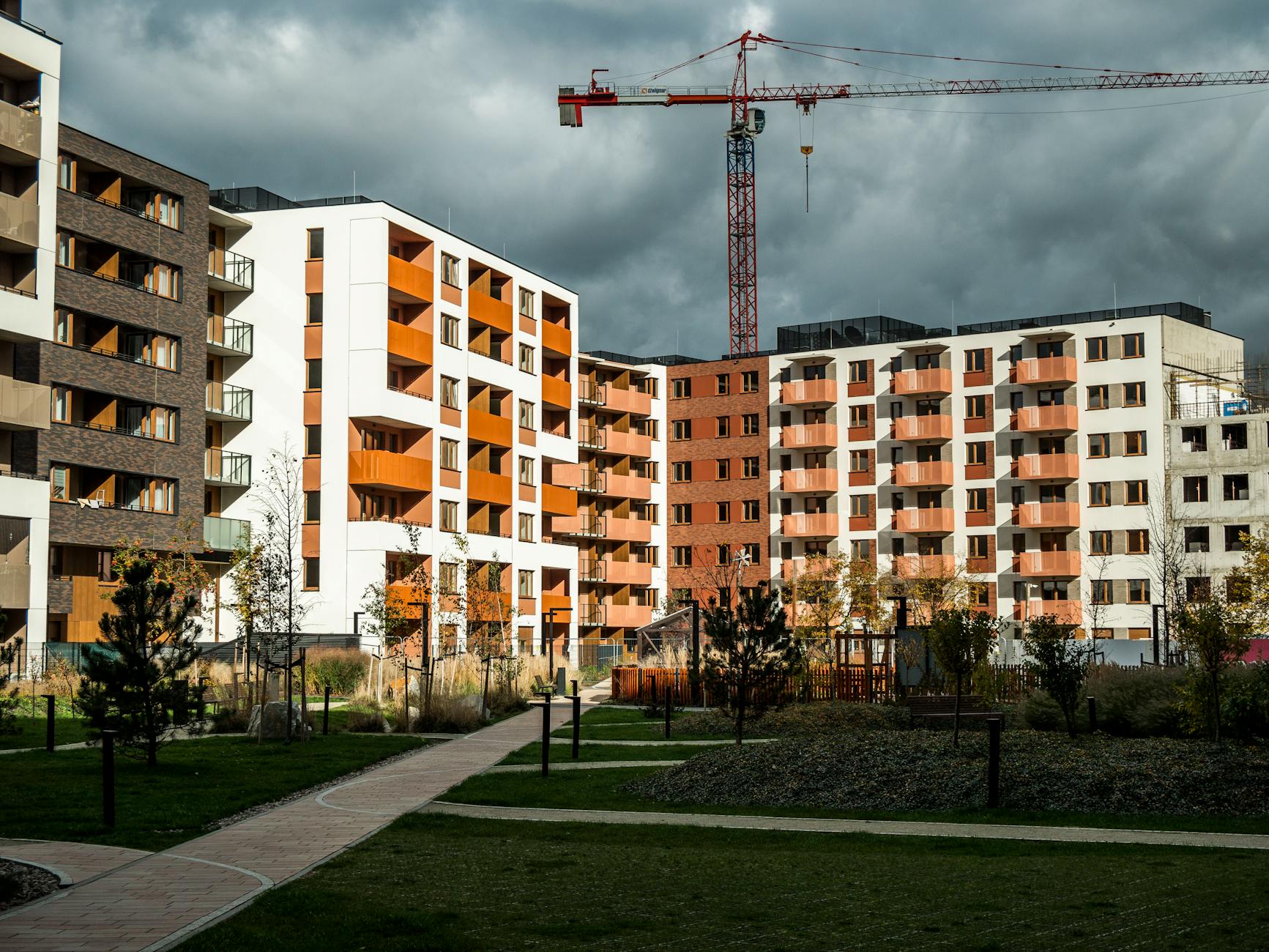 Newly built residential buildings under cloudy skies with a construction crane.